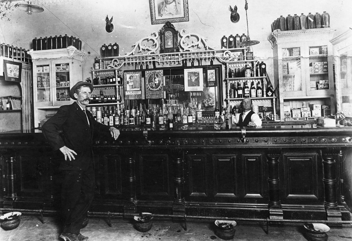 Interior of a long wooden saloon bar, circa 1900